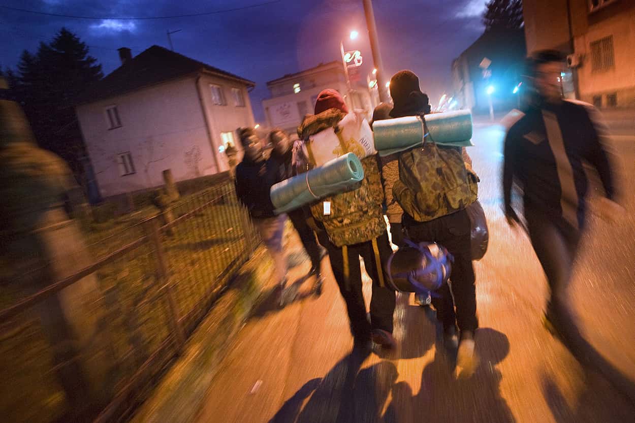 Mannelijke asielzoekers reizen lopend door een stad in de nacht